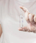 Person wearing Straight Up Premium Clear Vinyl Exam Gloves Large holding a clear vial, demonstrating safe handling.