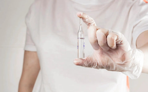 Person wearing Straight Up Premium Clear Vinyl Exam Gloves Large holding a clear vial, demonstrating safe handling.