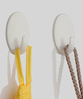 Heavy Duty Adhesive Wall Hooks For Bathroom And Kitchen Built Tough With Super Grip Oil Resistant Plastic Surface Mounts Zero Hole Punch Needed Fully Waterproof Set Of Three White Units holding a yellow strap and a brown rope.