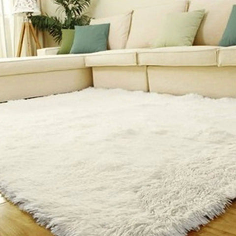 Plush white shag area rug with beige sectional sofa and green cushions in a bright living room.