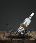 Handmade Asian Style Rickshaw Puller Wine Bottle Holder With Natural Rattan Accents, supports a wine bottle on a rustic surface.