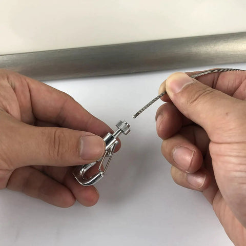 Hands attaching a steel cable to a hook from Click Rail Picture Hanging System Kit With Two White 59 Inch Rails Four Steel Cables Six Hooks
