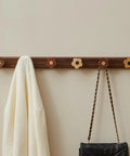 Dang Cute Flower Peg Wall Mount Coat Rack For Kids Crafted From Solid Walnut Wood Storage Perfect For Quick Hanging Heavy Backpacks Coats And Towels In Nurseries Without Any Setup Frustration mounted on wall with cream scarf and black purse.