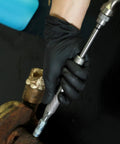 Heavy Duty Grease Fitting Cleaning Tool Zerk Cleaner Hammer in use on shaft bushing with gloved hand holding the tool