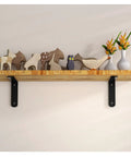 Top Tier Heavy Duty L Shaped Corner Brackets For Shelving Set Of 2 Black Metal Wall Mounts supporting a wooden shelf with decorative items.