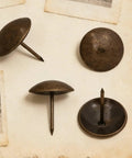 Heavy Duty Antique Brass Upholstery Tacks For Diy Furniture Repair Leather Crafting Auto Interiors Includes Thirty Solid Metal Clavos with round heads on a textured background.