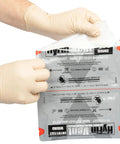 HyFin Vent chest seal twin pack, two units, in foil medical pouch being opened by gloved hands