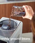 Hand pouring freshly ground beans into Super Automatic Espresso Maker With Smooth LatteGo Pro Milk Frother Brewextract Grind Boost.