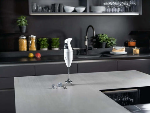 Top Shelf Swiss Made Classic Immersion Blender With 150W Motor And Two Speed Settings Whip Up Soups Smoothies Purees Like A Pro With Multipurpose Blade Beater And Whisk In White on kitchen counter.