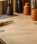 Two Brass Knife Pins For DIY Knife Handle Kits And Repairs on a wooden table with tools and a notebook nearby