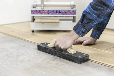 Person using Striker XXL Tapping Block No Mallet Needed For Mallet-Free Flooring Install Fast Safer Click-Together Planks Without Straining.