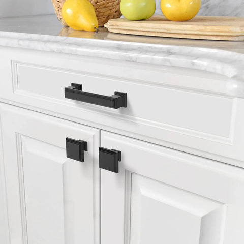 10 Pack 1.3 Inch 32mm Matte Black Cabinet Knobs on white kitchen cabinets next to fruit basket and cutting board