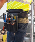 Tradesman Pro Tool Pouch With Tape Thong And Heavy Duty Reinforced Bottoms, attached to belt, holding tools on worker's side