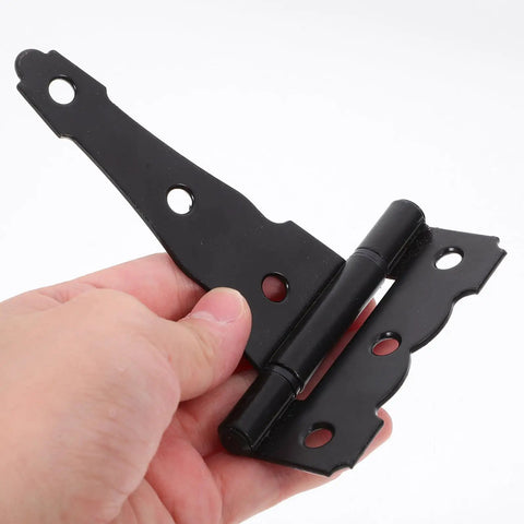 Hand holding 4 Inch T Shaped Barn Door Hinge Set Black Iron Heavy Duty Gate Hardware For Doors And Windows Matte Finish Provides Sturdy Support And Stability For Indoor Shed Barn And Exterior Use 2 Pcs against white background