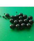 Twenty Piece Lot Of 1.588Mm Silicon Nitride Ceramic Balls G5 Grade, glossy black bearings on green surface.