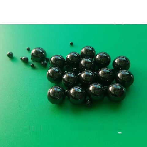 Twenty Piece Lot Of 1.588Mm Silicon Nitride Ceramic Balls G5 Grade, glossy black bearings on green surface.