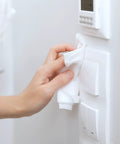 Premium 96 Percent Isopropyl Alcohol Wipes Bulk Pack Comes Packed With 1000 Lint Free SMS Cloth sanitizing a light switch.