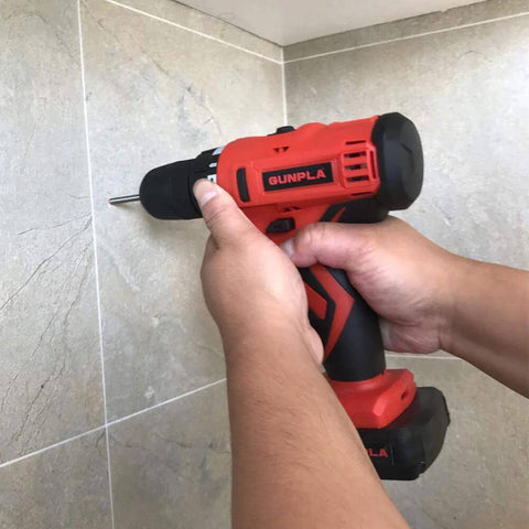Gunpla cordless drill, red and black, with bit, drilling into tiled wall