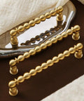 Brushed Brass Ball Drawer Knobs and Cabinet Pulls Set for Kitchen Cabinets and Furniture Hardware on a reflective surface