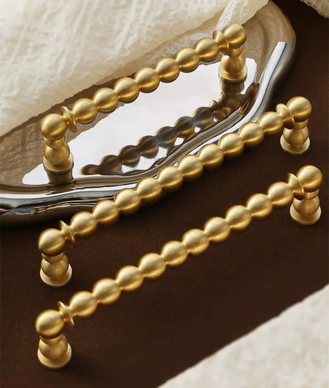 Brushed Brass Ball Drawer Knobs and Cabinet Pulls Set for Kitchen Cabinets and Furniture Hardware on a reflective surface