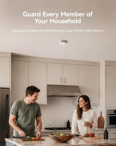 Hassle Free Smoke Detector Designed With Adaptive Sensing To Slash Nuisance Alerts While Delivering Dependable Household Fire Protection Runs Smooth On A Single Nine Volt Battery Offers Quick Easy Wall Install mounted on kitchen ceiling above couple preparing food.