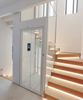 Hassle Free Residential Home Elevator No Pit Or Machine Room For Existing Homes, compact glass lift next to illuminated stairs.