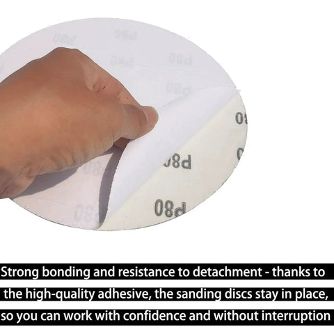 Hand peeling back an 8-inch self-adhesive 80 grit sandpaper disc from 30 Pack 8 Inch Self Adhesive Sanding Discs Set Grit 80 100 120 180 240 400 For Drywall Floors Woodworking And Metal Projects Sticky Back Sandpaper Discs Great For Paint Prep Rust Busting Deburring And Smoothing
