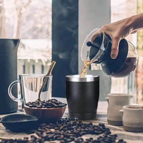 Built Tough 304 Stainless Steel Insulated Travel Mug keeping your morning grind fresh, filled with hot coffee, on a table with coffee beans.