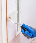 Hand holding a mini roller with a white sponge cover painting a wall, demonstrating the Ten Pack Of White Sponge Paint Roller Covers For Walls And Ceilings No Drama Mini Size Slick Operation Great For Diy Renos Quick Change Design Smooth Operator Finish Every Time.