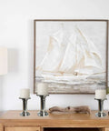Three stainless steel candle holders on a wooden table with nautical painting in the background, modern home decor on display