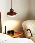Wood Grain Pendant Light, 3 Color LED Resin Hanging Fixture for Bedroom above a cozy bed with textured shade.