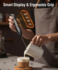Person using Rechargeable Electric Milk Frother Handheld 3 In 1 With LED Display And Wireless Charging 3 Speeds Stainless Steel Whisk For Latte And Cappuccino Foam Pro Grade Battery Monitoring Easy Clean Bright Grey to froth milk into coffee.