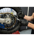 Tusk heavy-duty chain breaker rivet tool side view being used on a motorcycle chain, black-gloved hands