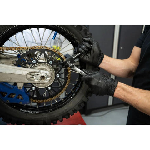 Tusk heavy-duty chain breaker rivet tool side view being used on a motorcycle chain, black-gloved hands