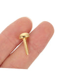Close-up of a single golden paper fastener for scrapbooking projects, shown between fingers for scale.