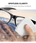 Lens cleaning microfiber cloth; white cloth used to wipe black eyeglasses (close-up).