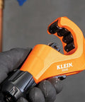 Tubing cutter Klein 50046 Constant Swing in orange, held by gloved hand