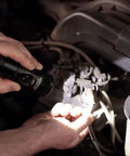 Mechanic using Stinger LED Rechargeable Flashlight With 12V DC Smart Piggyback Charger Beefy Rugged Aluminum Body in a car engine