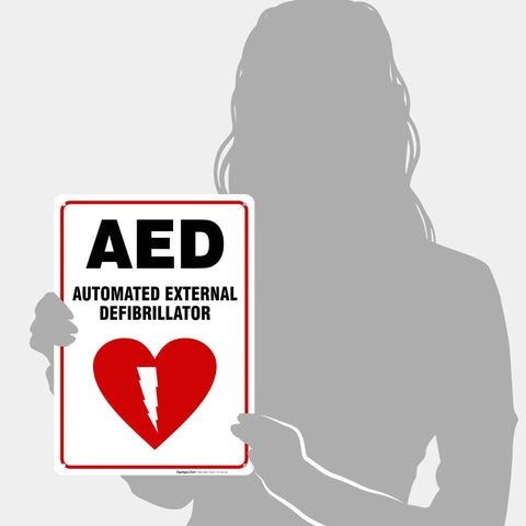 AED defibrillator sign held by silhouette; 10x14 inch white HDPS sign with red border and heart with lightning bolt.