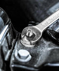 Grease zerk fitting installed in a metal housing; close-up view with wrench tightening.