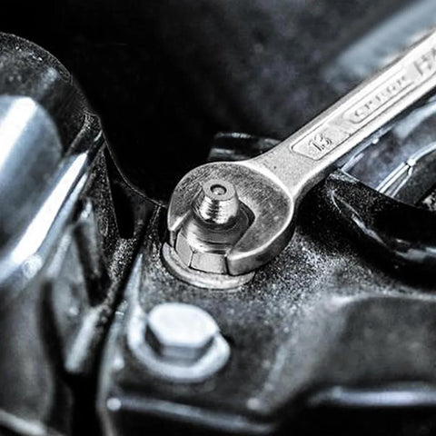 Grease zerk fitting installed in a metal housing; close-up view with wrench tightening.