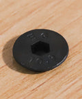 Close-up of top view M5 flat head socket cap screw, black oxide finish, 10.9 grade alloy steel, focus on hex socket and engravings.