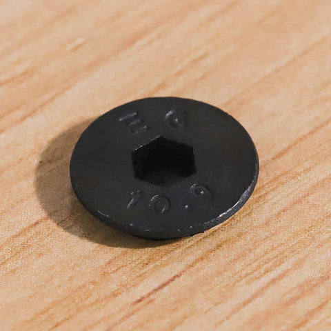 Close-up of top view M5 flat head socket cap screw, black oxide finish, 10.9 grade alloy steel, focus on hex socket and engravings.