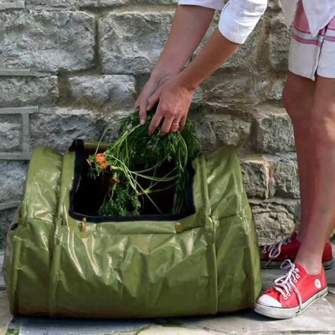 Person adding waste to Roll Mix Compost Bin Tumbler For Home Garden Green 41 Gallon Capacity 26 Inches Wide Hassle Free