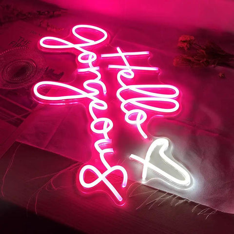 Hello Gorgeous Pink LED Neon Sign For Wall Decor, 21 Inch Neon Light in pink with heart design on a wooden table.