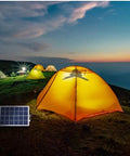 Premium Solar Pendant Light With Remote Control And Sixty Leds illuminates a yellow tent in a camping setting at dusk.