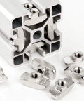 50 Pack 4040 Series M6 T Slot Nuts Hammer Head Fasteners For Aluminum Profiles Nickel Plated Carbon Steel Nut Rust Resistant Easy Install Heavy Duty T Nuts For 4040 Extrusion shown next to an aluminum profile.