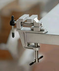 Heavy Duty Aluminum Bench Vise With Mini Clamp For DIY Jewelry Making And Electronics Repair secured on a wooden workbench.