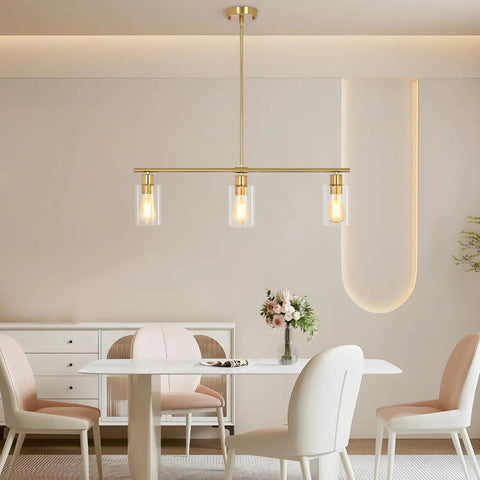 3-Light Kitchen Island Pendant Lighting in Gold Finish over dining table, featuring clear glass shades and modern design.