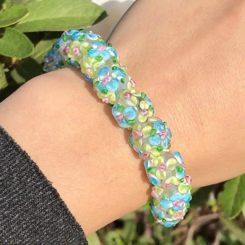 Score These Hella Rad Lampwork Glass Round Spacer Beads With Big Center Holes Perfect For DIY Jewelry Making Kicking Up Your Bracelet And Necklace Crafting Vibes Today. Colorful bracelet made of lampwork glass beads on a wrist.